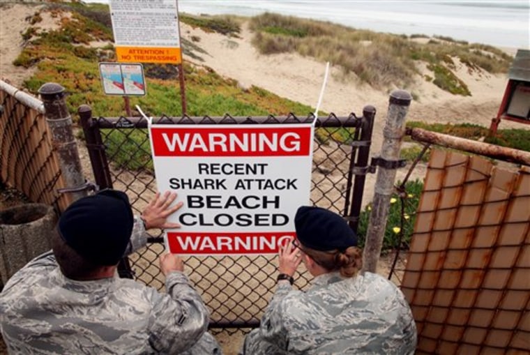 Airmen 1st class Daniel Clark, left, and Staff Sgt. Keri Embry, post a sign warning surfers of a recent shark attack Friday, Oct. 22, 2010, at Vandenburg Air Force Base, Calif. Lucas Ransom, 19, was boogie-boarding in the surf line about 100 yards off of Surf Beach with a friend when a shark suddenly pulled him under the water shortly before 9 a.m., according to a statement from the Santa Barbara County Sheriff's Department. Surf Beach, 130 miles northwest of Los Angeles, is on the property of Vandenberg Air Force Base but is open to the public. (AP Photo/Spencer Weiner)